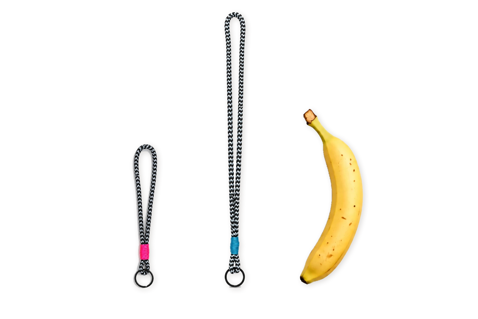 *gyst Schlüsselbänder drop 001: kurzes Band mit pinker Wicklung und langes Band mit blauer Wicklung, schwarz-weisses Seilgeflecht und schwarze Ringe, daneben eine Banane als Grössenvergleich.
